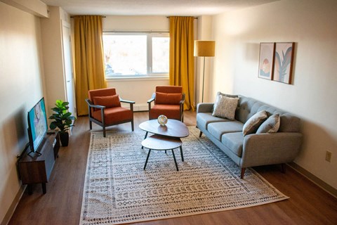 a living room with a couch and chairs and a tv